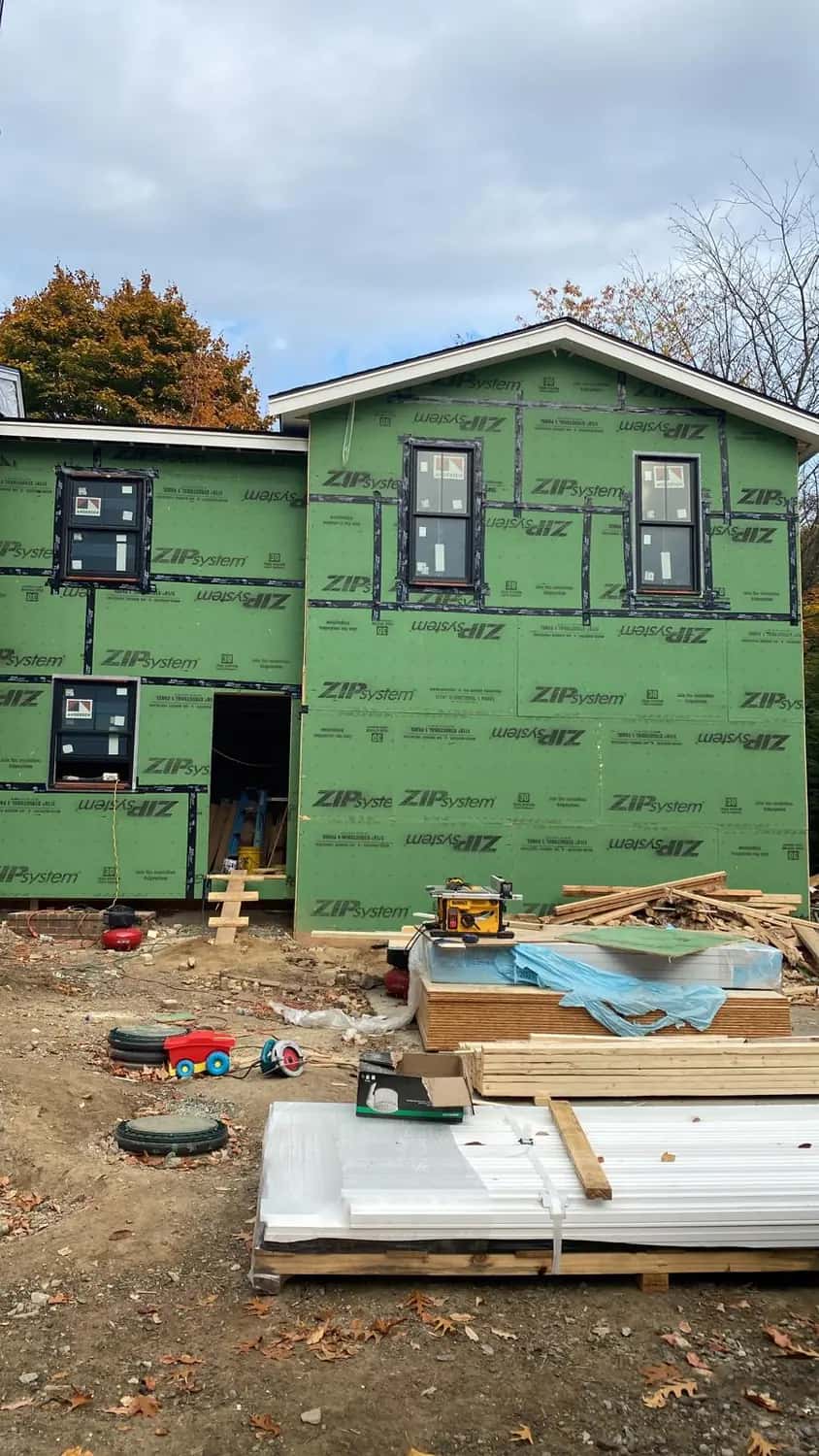 Back of a two-story addition in taped green sheathing with new windows installed